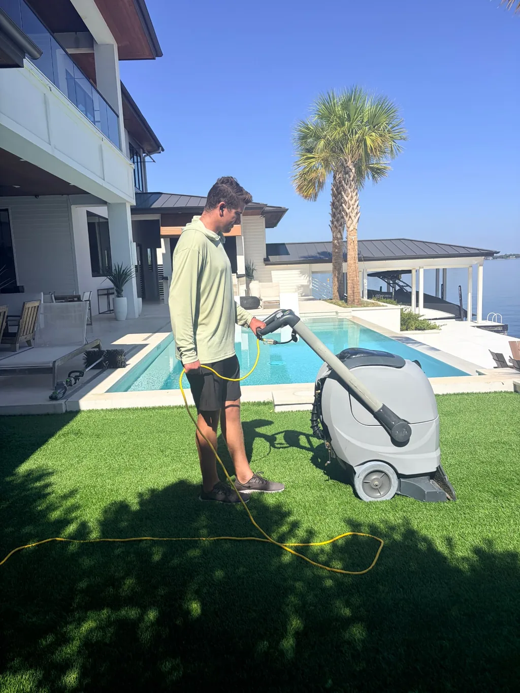 Extraction machine pulling dirty rinse water out of artificial turf beside a swimming pool